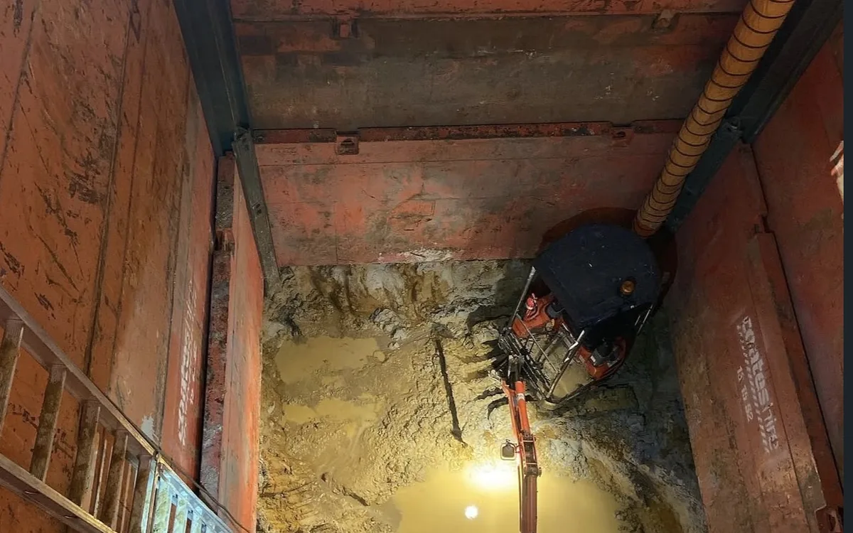 Machine working at the base of a deep shaft during underground services work