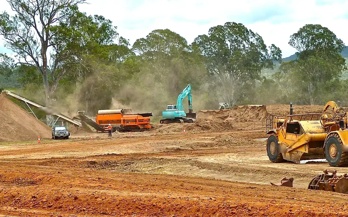 Bulk excavation site with excavators and tipper trucks working a deep basement cut